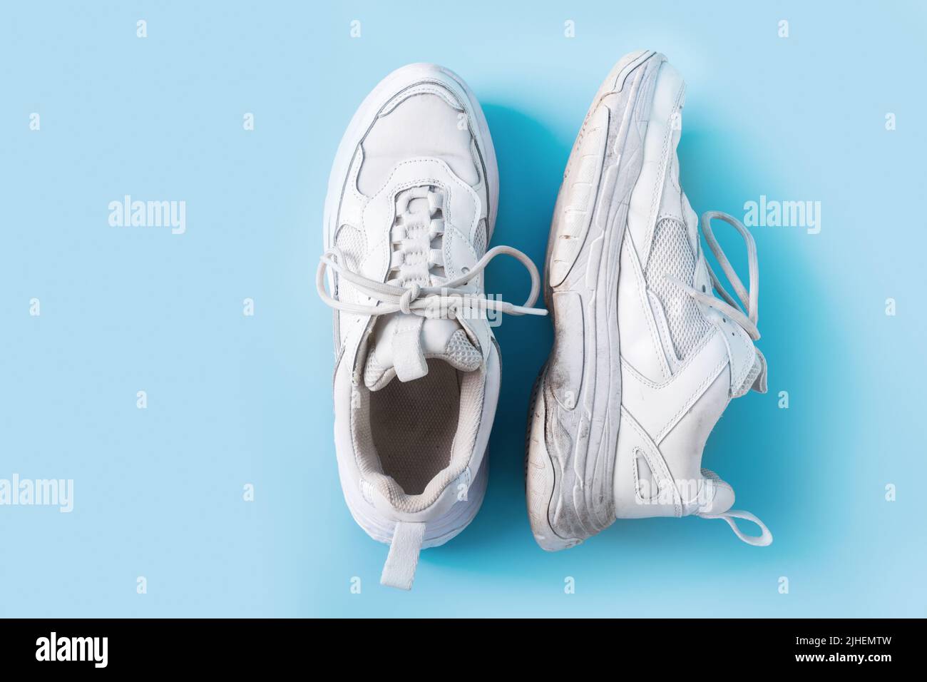 Schmutzige alte weiße Sneakers auf blauem Hintergrund. Stockfoto