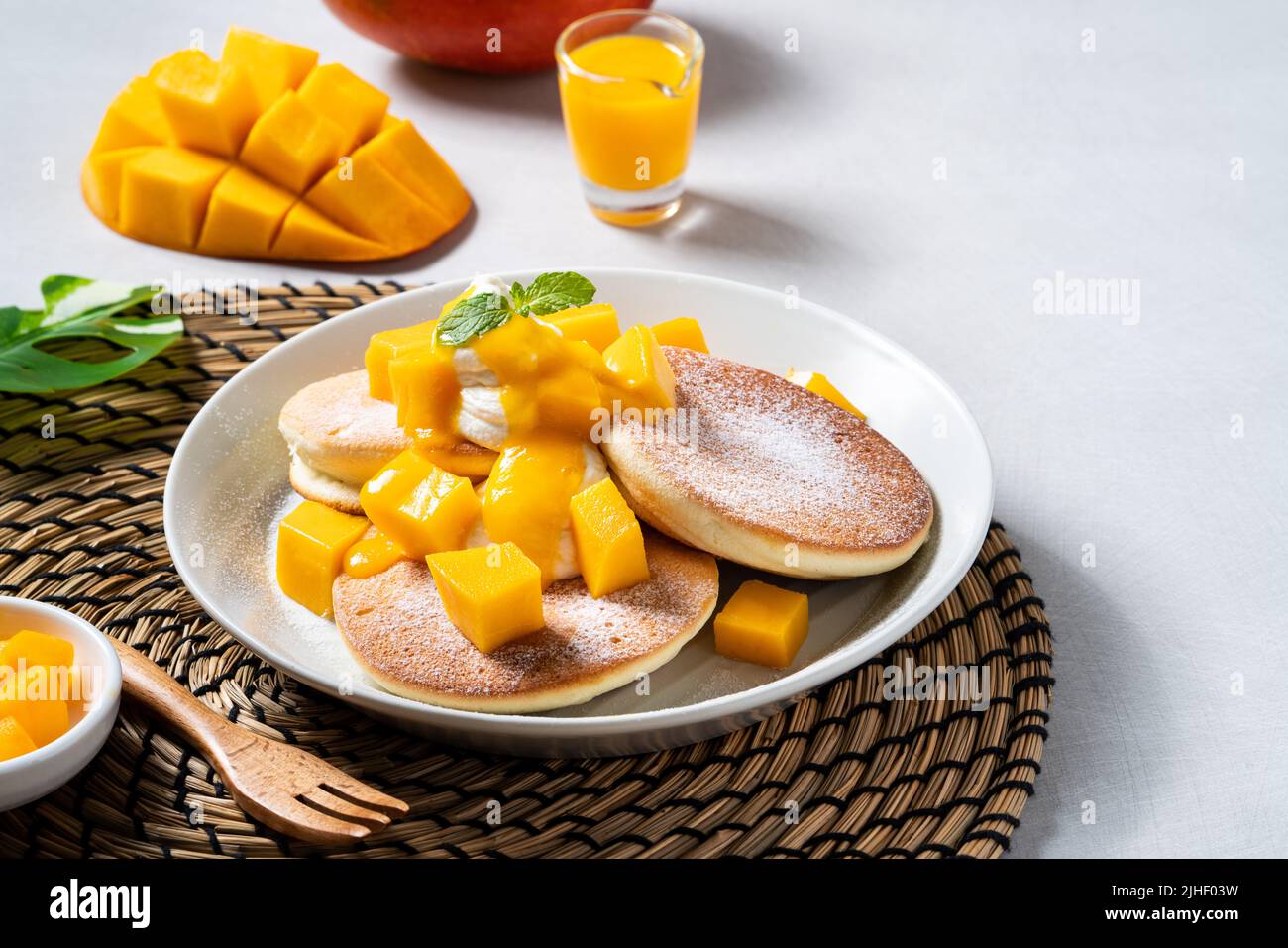 Köstlicher japanischer Souffle-Pfannkuchen mit würfelnem Mango-Fruchtfleisch und Marmelade auf weißem Tischhintergrund. Stockfoto