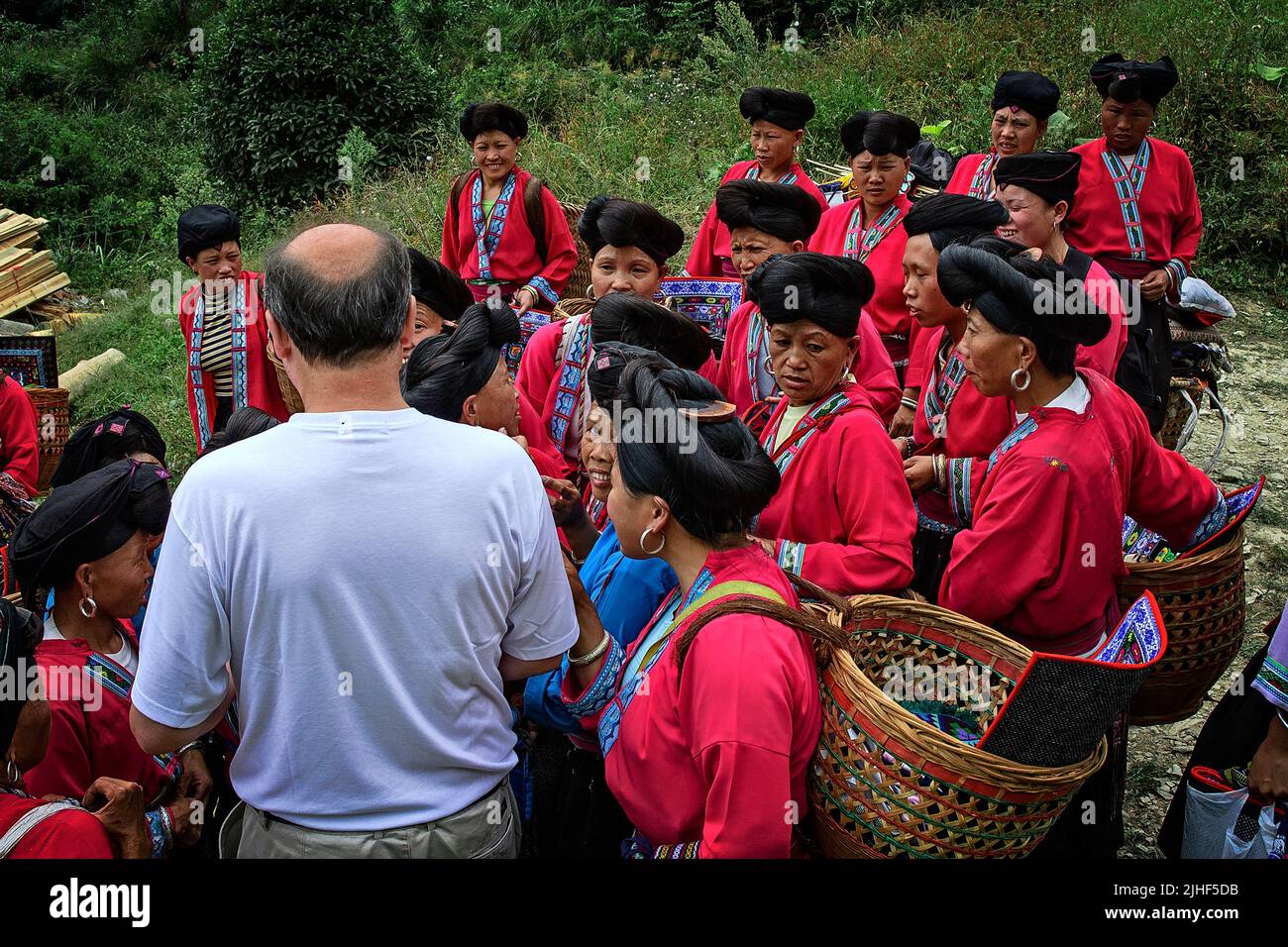 Weißer Mann besucht eine Gruppe von Zhuang Frauen in Ping'an, Longsheng, China. Stockfoto