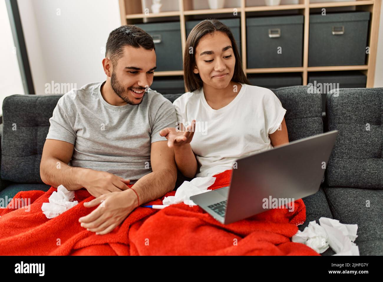 Junge lateinamerikanische kranke Paare, die zu Hause eine medizinische Fernsulation mit einem Laptop haben. Stockfoto