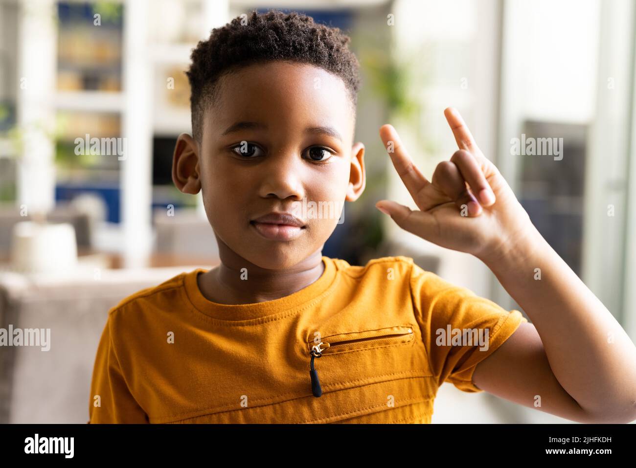 Bild eines lächelnden afroamerikanischen Jungen mit Gebärdensprache Stockfoto