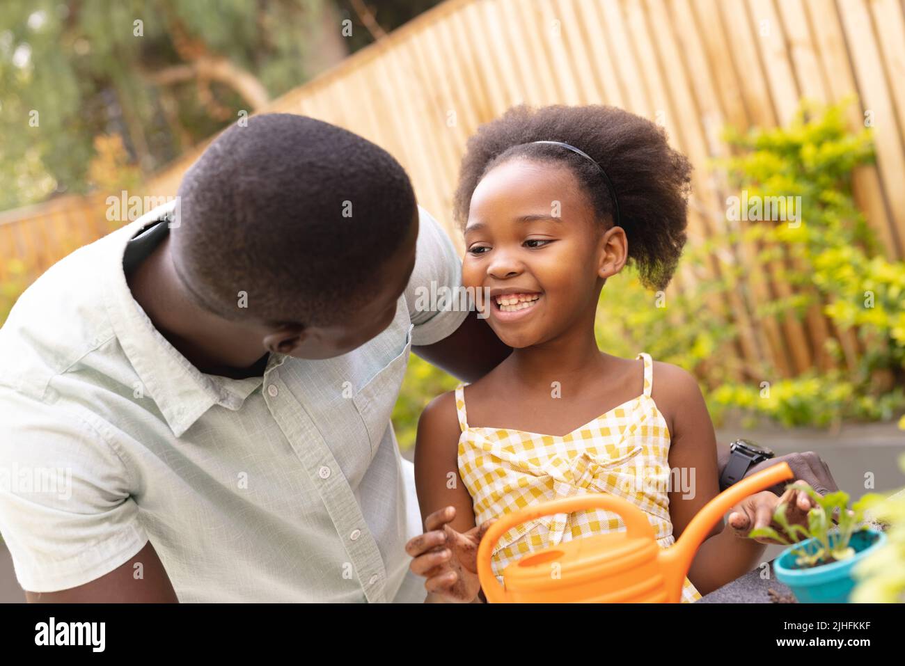 Bild eines glücklichen afroamerikanischen Vaters und einer Tochter, die gemeinsam gärtnerisch arbeiten Stockfoto