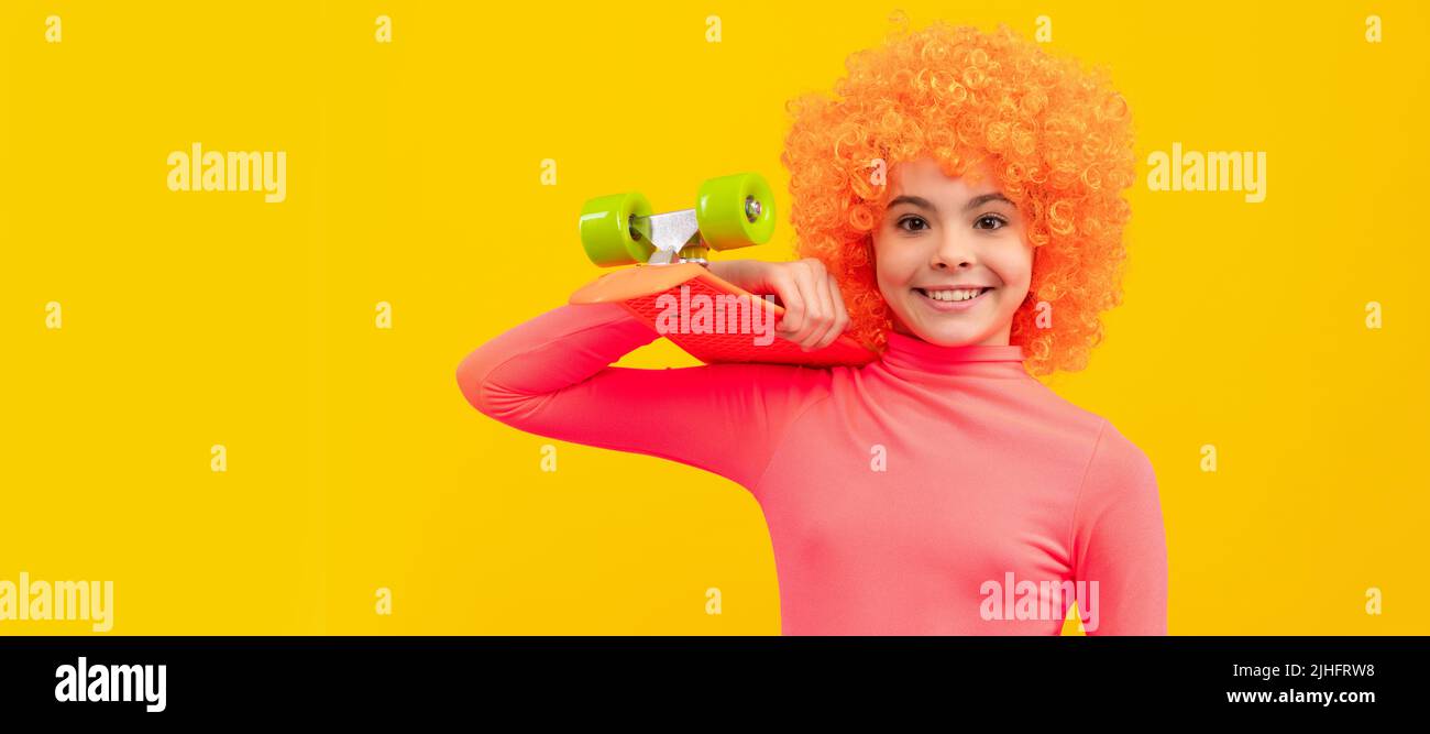 Glückliches Mädchen Kind mit orangefarbenen Haaren in rosa Poloneck Lächeln hält Pennyboard, Pennyboard. Lustige Teenager Kind auf der Party, Poster Banner Header mit Stockfoto