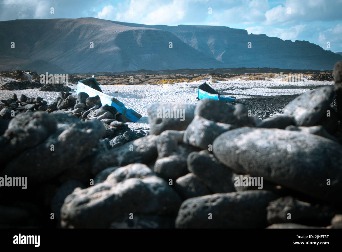 Blaue alte Holzboote am weißen Strand von Caleta del Mojon Blanco. Sandiger Wüstenstrand und zerklüftete Küste. Orzola, Lanzarote, Kanarische Inseln, Spanien Stockfoto