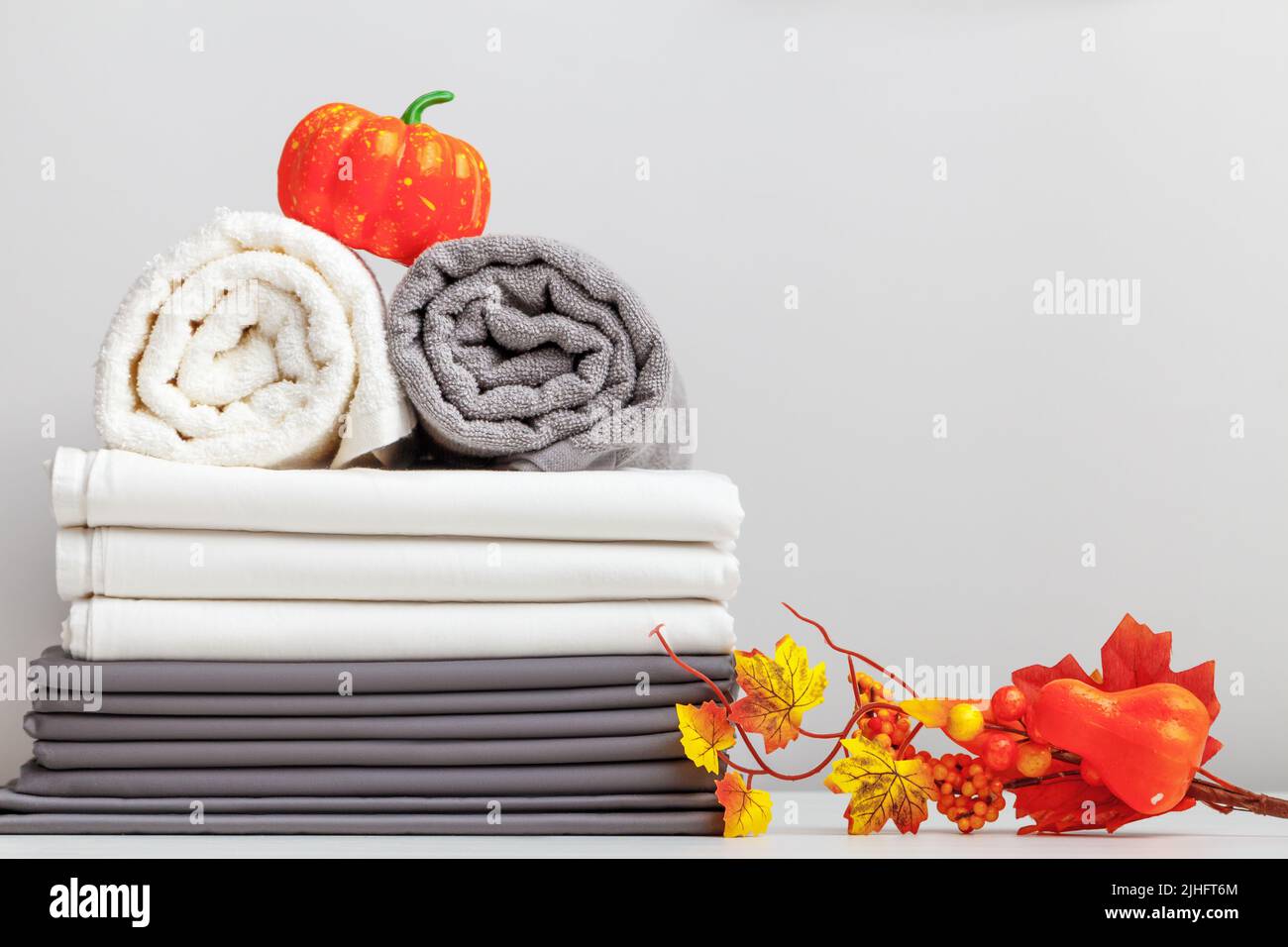 Halloween-Dekor. Grau-weiße Bettwäsche, ein Laken und zwei Handtücher auf dem Tisch. Stockfoto