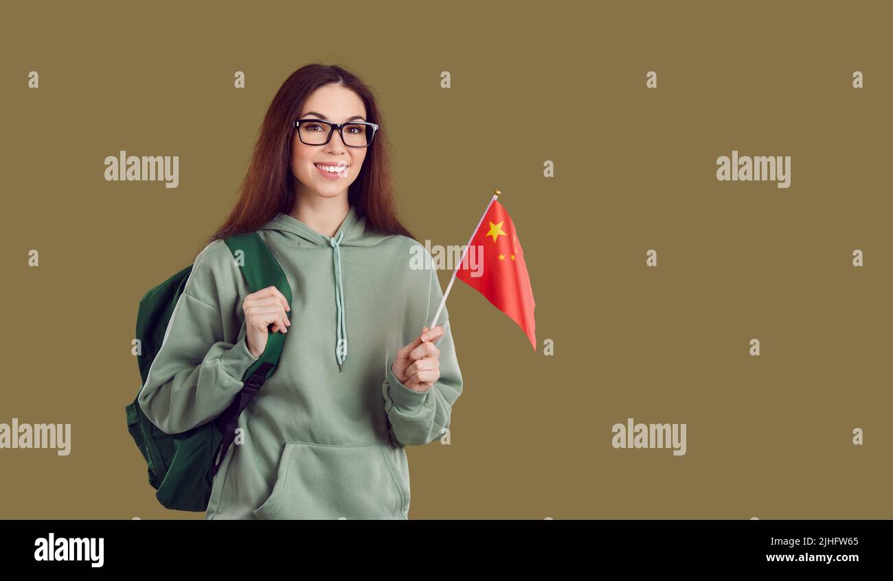 Lächelnder Student mit Rucksack hält chinesische Flagge Stockfoto