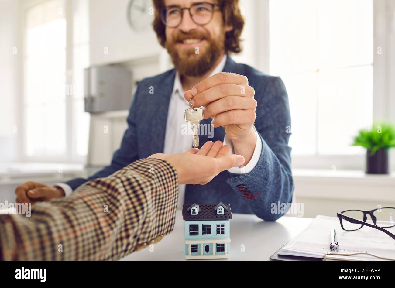 Glückliches Lächeln Immobilienmakler gibt seinem Kunden die Schlüssel zu ihrem neu gekauften Haus Stockfoto