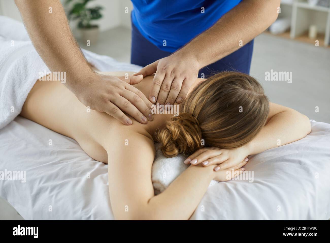 Masseur Massage weibliche Klientin Kampf mit Rückenschmerzen Stockfoto