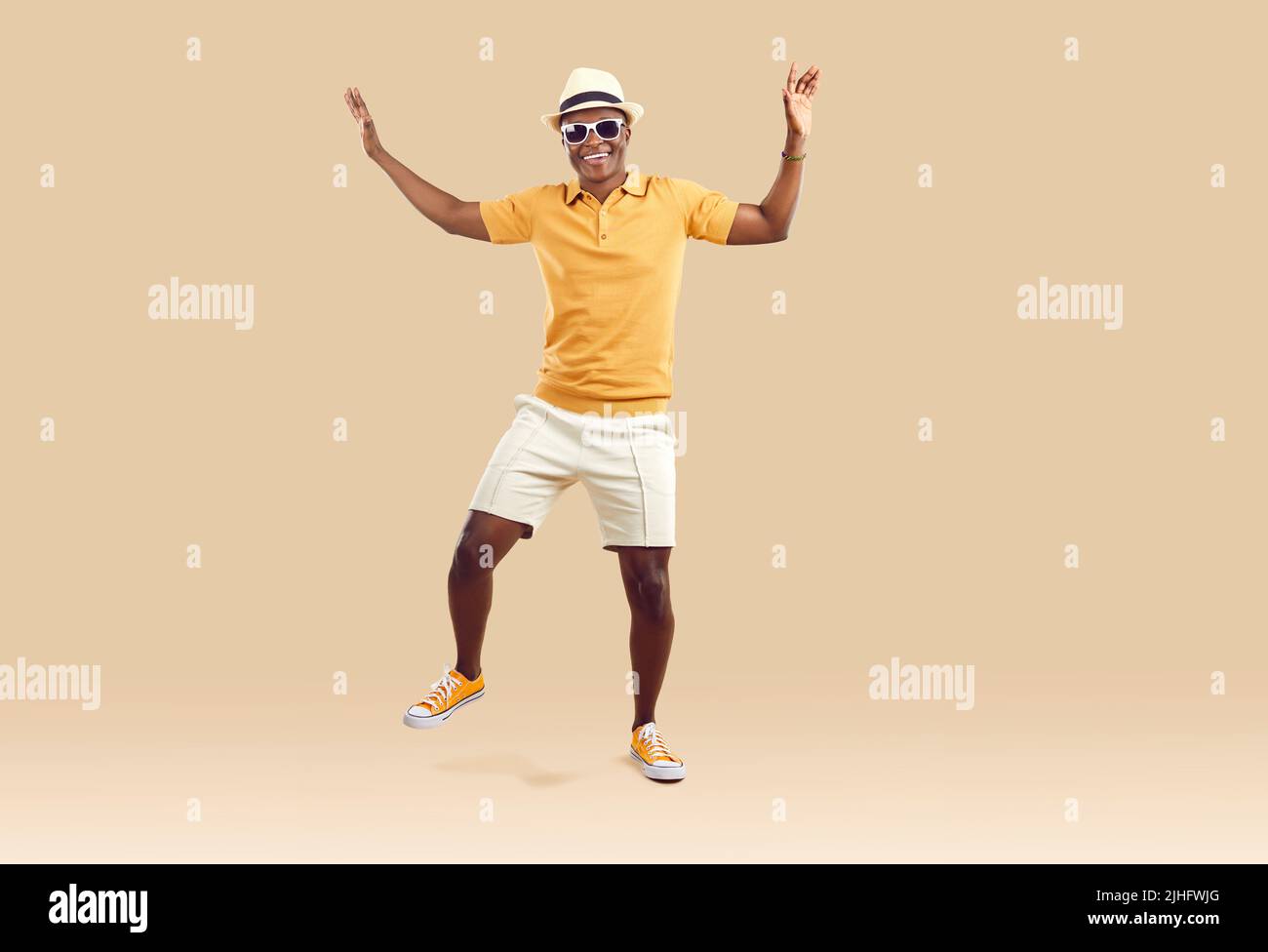 Cool fröhlich afroamerikanischen Mann lustig Jubel und Tanz isoliert auf beigem Hintergrund. Stockfoto
