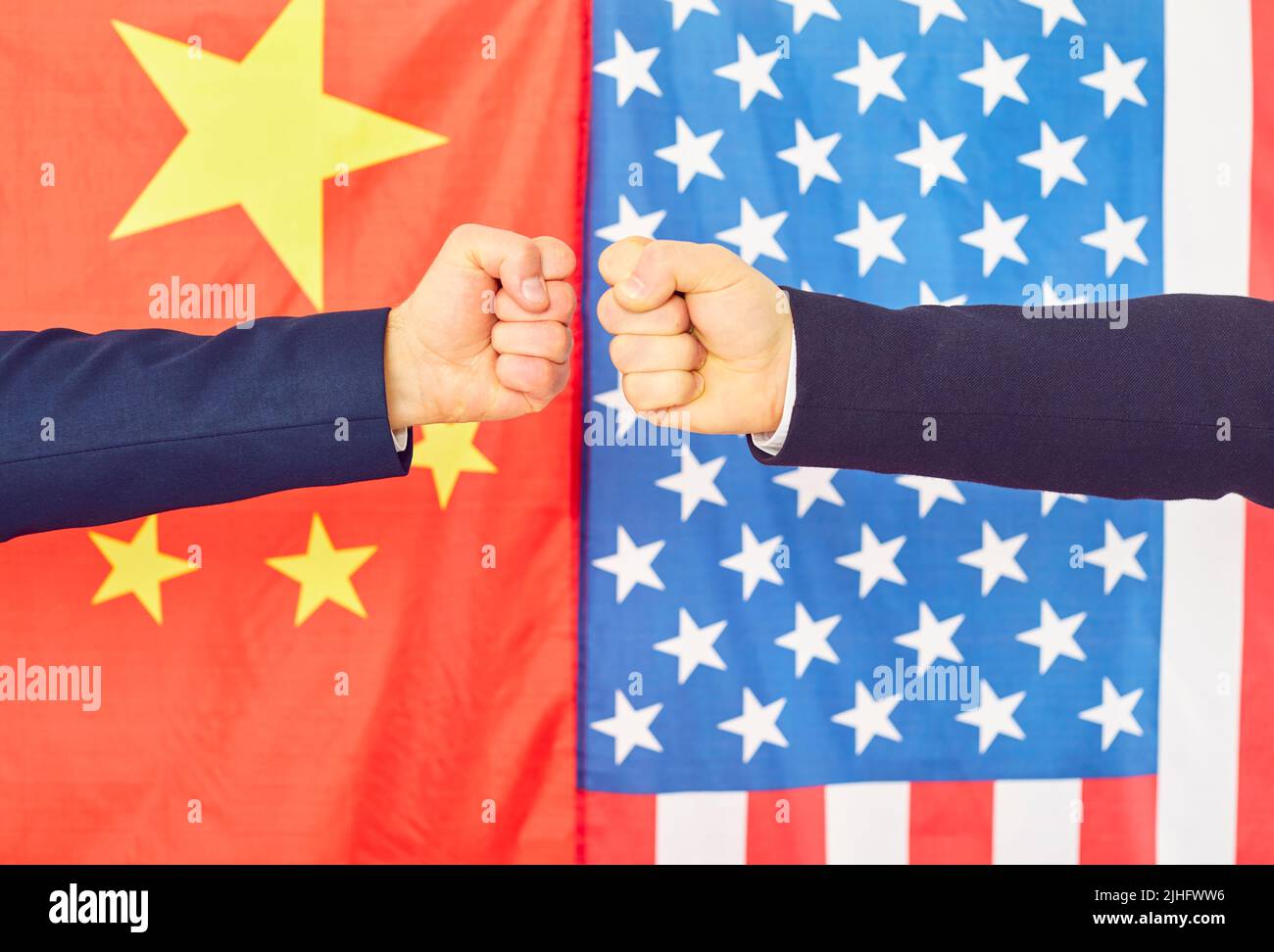 Fäuste vor dem Hintergrund chinesischer und amerikanischer Flaggen als Symbol für Konfrontation und Meinungsverschiedenheiten. Stockfoto