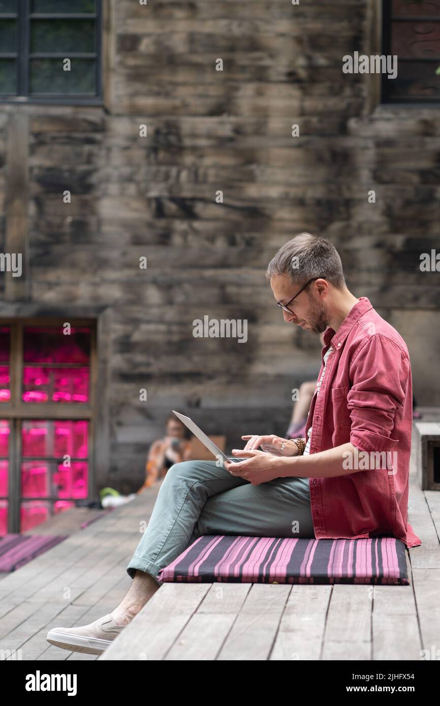 Fokussierter Mann freiberuflicher Web-Entwickler, der Code schreibt, während er im Außenbüro am Laptop arbeitet Stockfoto