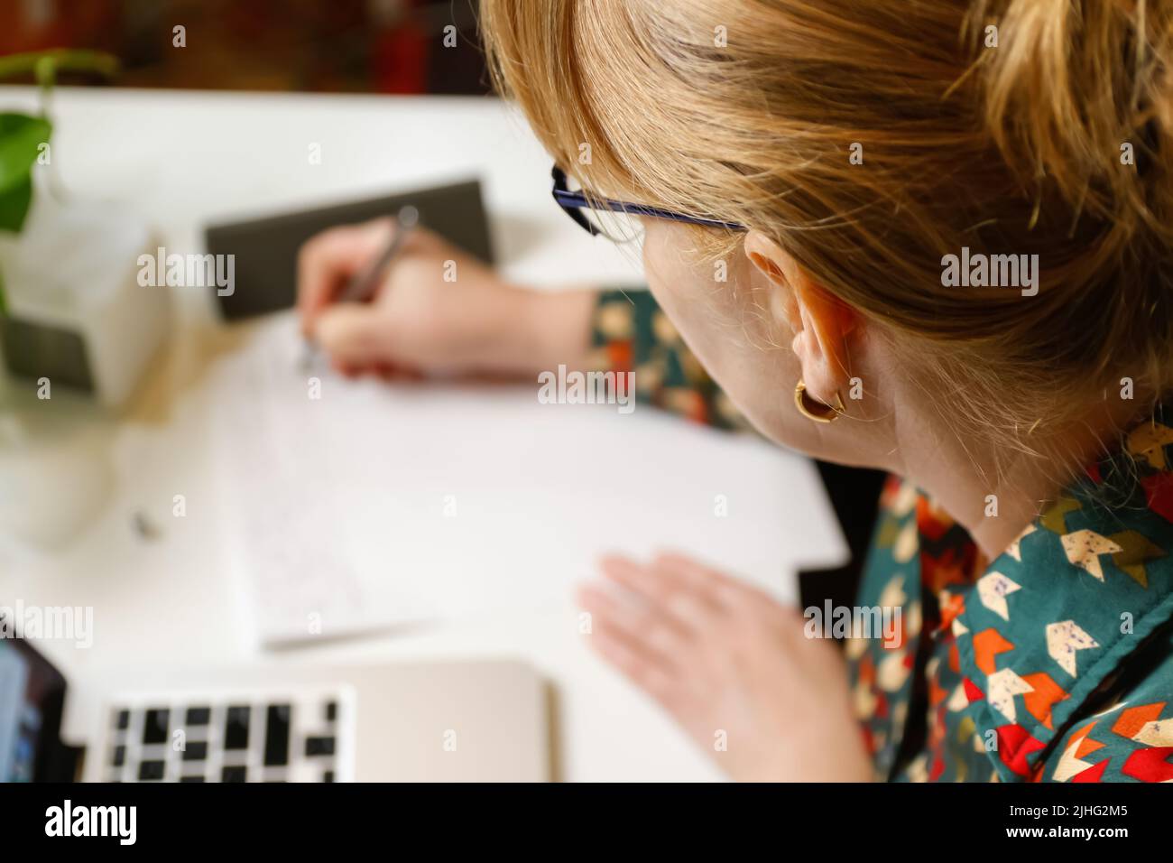 Defokussieren weiblicher Hand Schreibfeder. Unkenntlich elegante Frau, die im Büro am Computer arbeitet. Beginn oder Ende eines Arbeitstages. Arbeitsbereich. Papierkram. Zeit Stockfoto