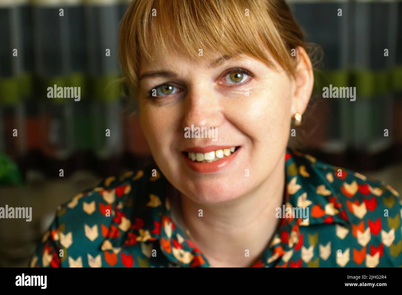 Unschärfe-Nahaufnahme Innenportrait der schönen jungen blonden Frau auf dem Hintergrund zu Hause. Blonde Frau lächelt. Frau 40s. Psychische Gesundheit, Stille. Aus Stockfoto