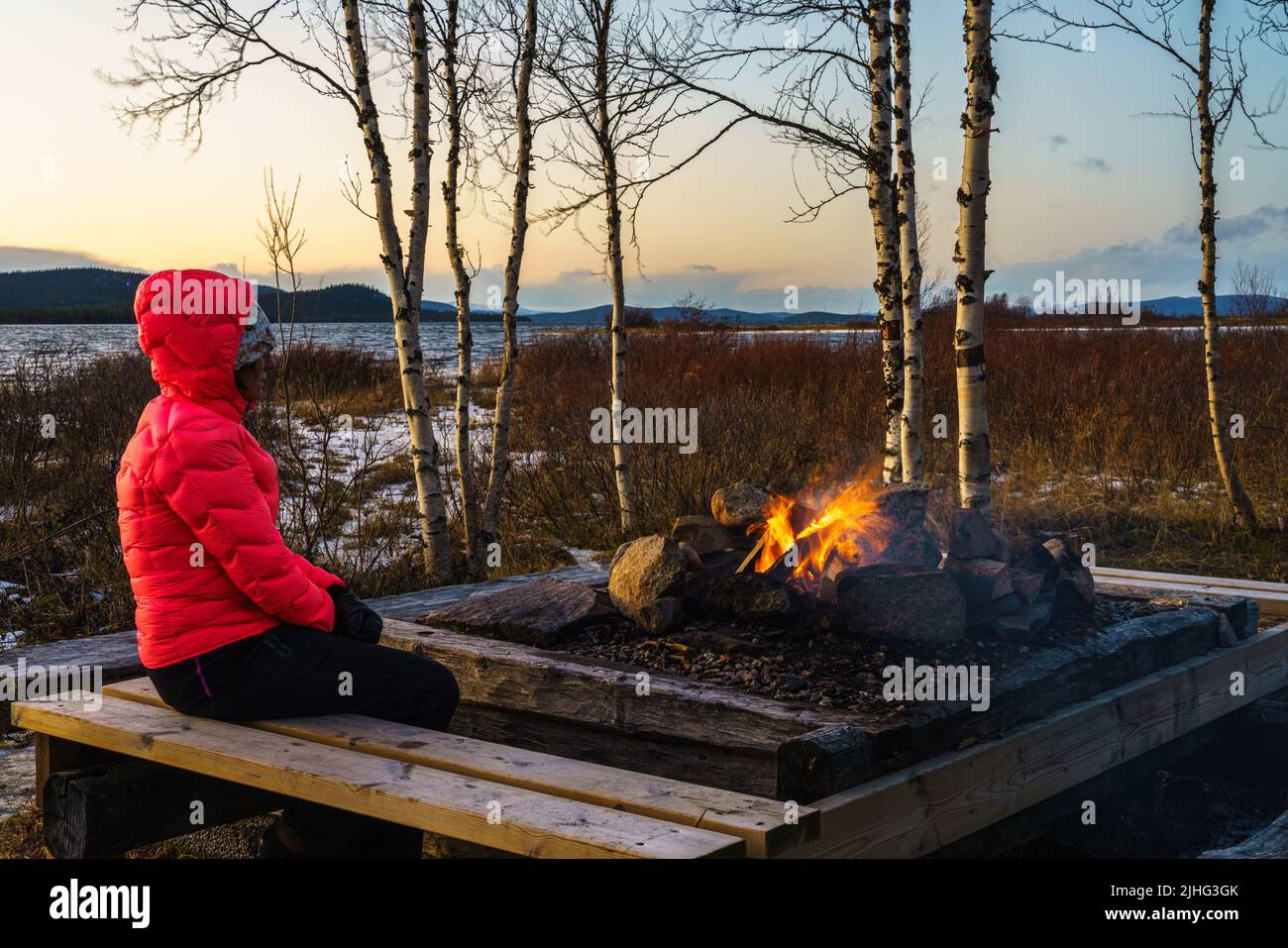 Frau, die in der Herbstsaison am Feuer sitzt, Gällivare County, Schwedisch Lappland, Schweden Stockfoto