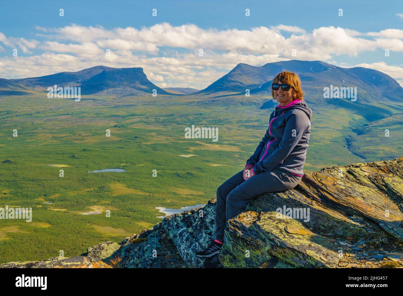 Frau auf einem Felsen auf dem Berg Nuolja mit Lapporten, Tjuonavagge im Hintergrund, Abisko, Schwedisch Lappland, Schweden Stockfoto
