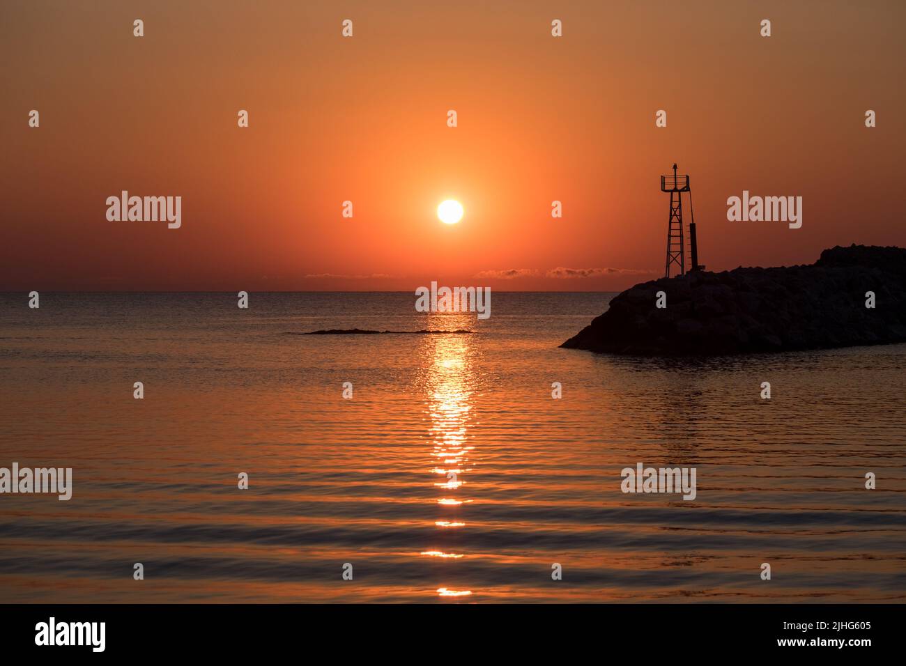 Sonnenaufgang Meereslandschaft mit einem Leuchtturm und der Reflexion der Sonne im Wasser Stockfoto