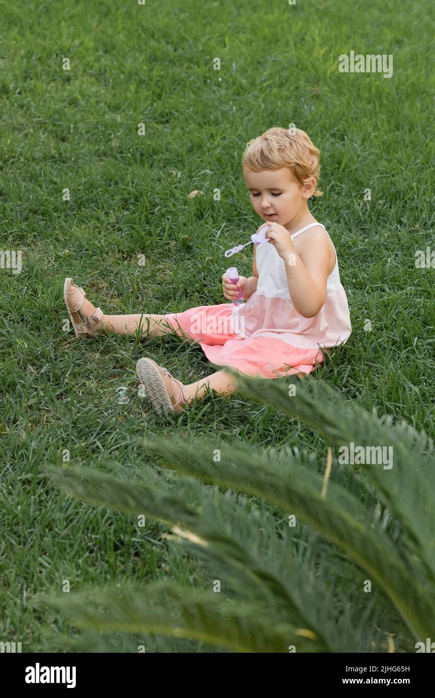 Kleinkind Kind hält Seifenblasen und sitzt auf Gras im Freien Stockfoto