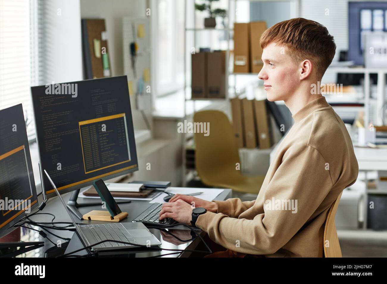 Junger Computerprogrammierer, der auf Web site Projekt in der Software arbeitet, die auf Desktop-Computer im Unternehmen entwickelt Stockfoto