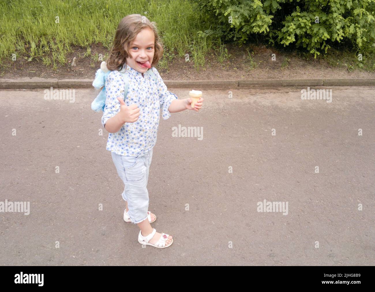 Lustige blonde blauäugige Mädchen mit Eis aufgesticht Zunge, zeigt wie Geste. Frech verspielt. Stockfoto