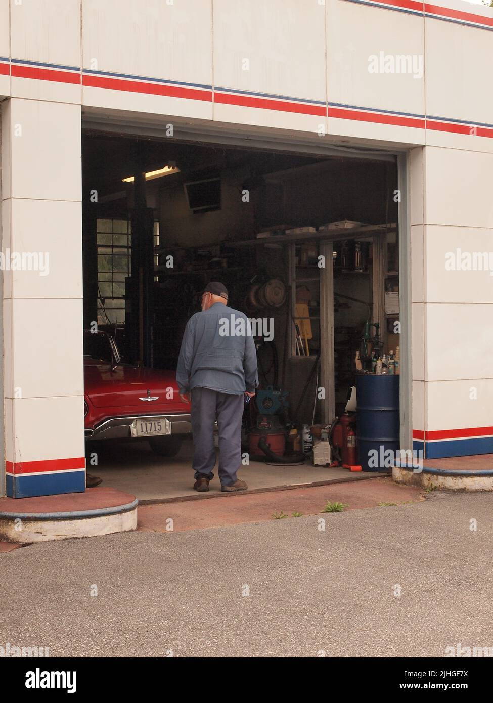 Ein klassischer roter Ford Thunderbird aus dem Jahr 1957, der in einer traditionellen Tankstelle in Pennsylvania zu sehen ist. Der Besitzer kann gesehen werden, wie er am Auto arbeitet. Stockfoto
