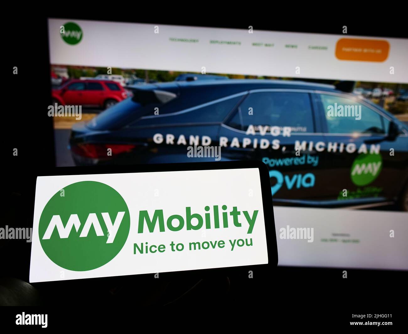 Person, die Mobiltelefon mit dem Logo des amerikanischen selbstfahrenden Unternehmens May Mobility Inc. Auf dem Bildschirm vor der Website hält. Konzentrieren Sie sich auf die Telefonanzeige. Stockfoto