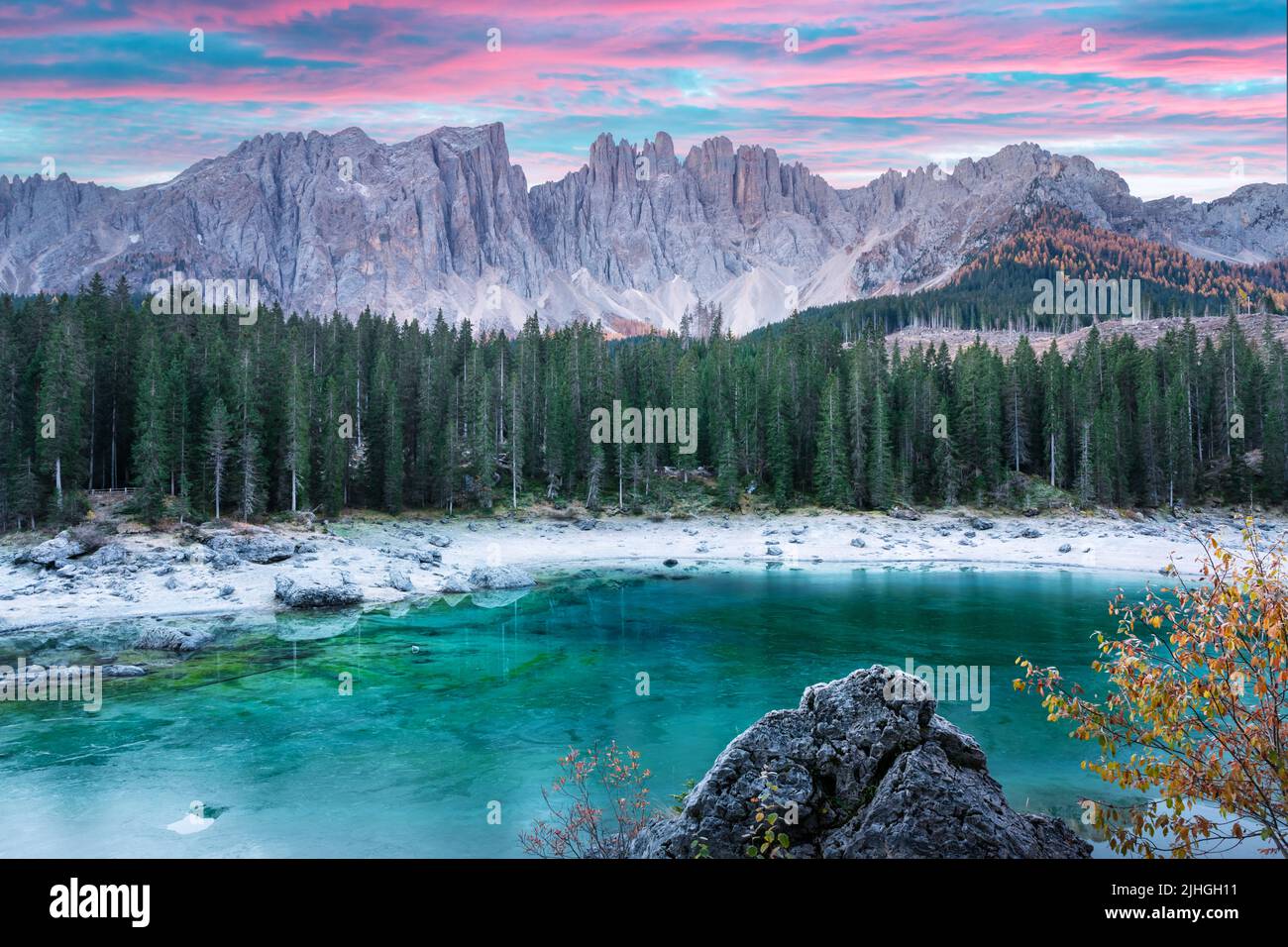 Malerischer Blick auf den gefrorenen Karersee in der Provinz Bozen - Südtirol. Rosafarbener Sonnenaufgang in den italienischen Dolomiten. Landschaftsfotografie Stockfoto