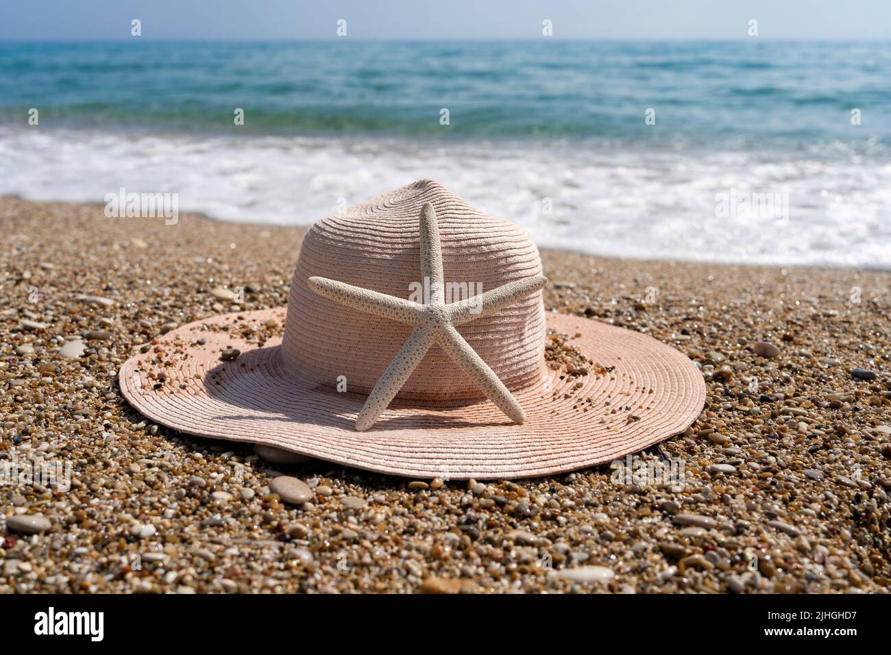 Seesterne mit Strohhut am schönen Sandstrand im Mittelmeer Stockfoto