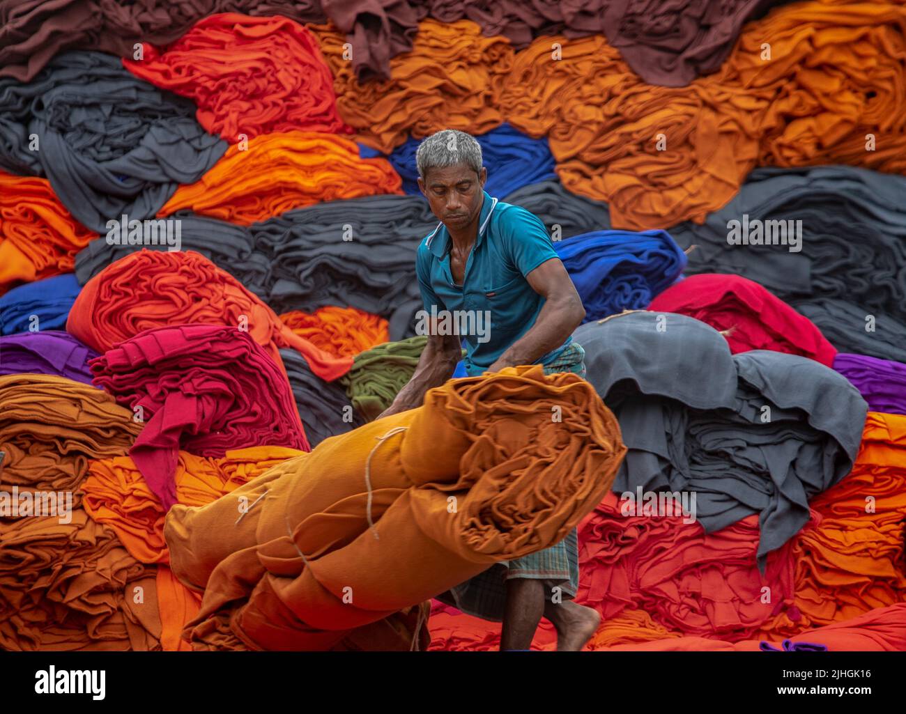 Bunte Decken werden von Arbeitern auf LKWs geladen. Textilindustrie in Bangladesch Stockfoto