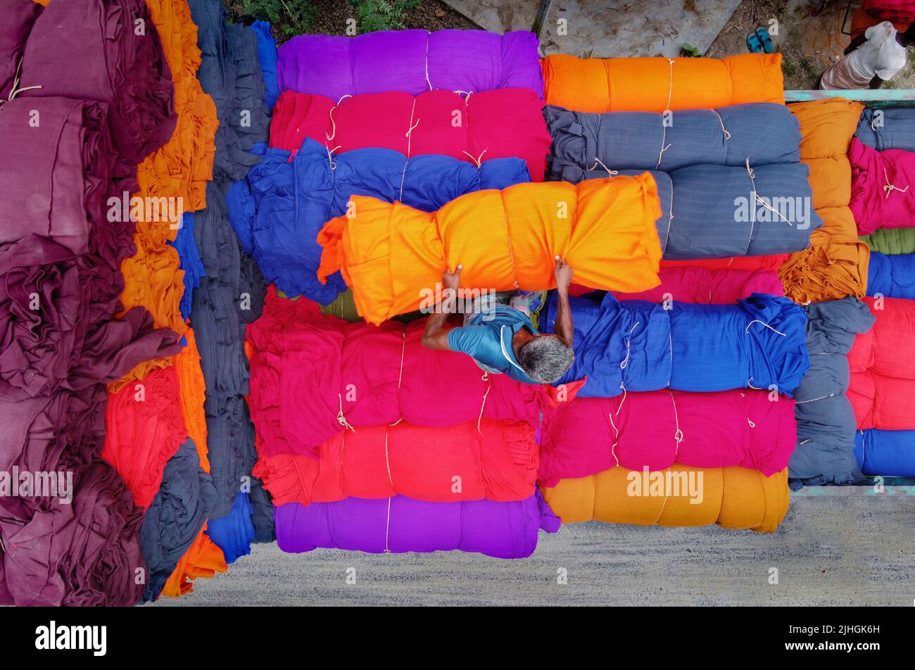 Bunte Decken werden von Arbeitern auf LKWs geladen. Textilindustrie in Bangladesch Stockfoto