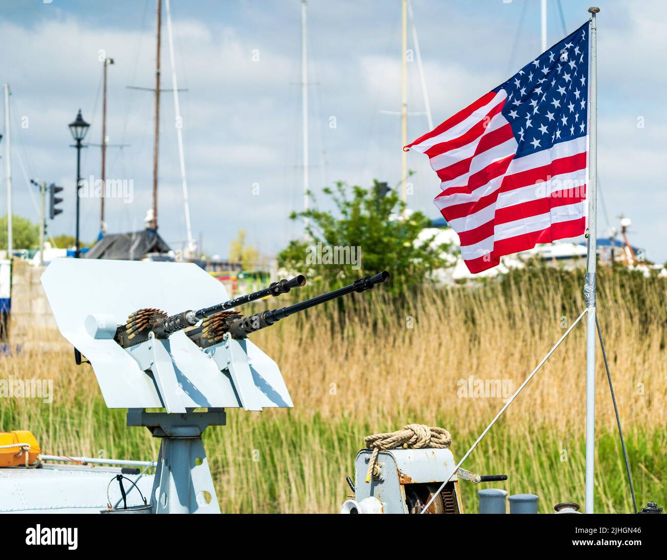 Amerikanische Flagge flattert im Wind neben einem Zwillings-Revolver mit M1919 Browning-Maschinengewehr auf dem Bogendeck des US-Marine-Patrouillenbootes, P22 in Sandwich, Ken Stockfoto