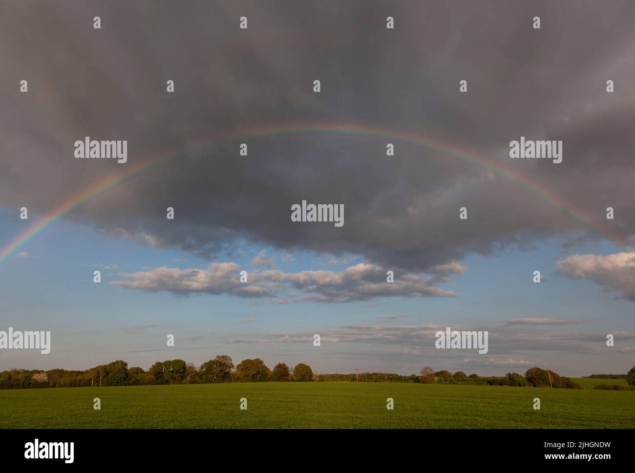Ein voller Regenbogenbogen in den Wolken über der Landschaft Stockfoto