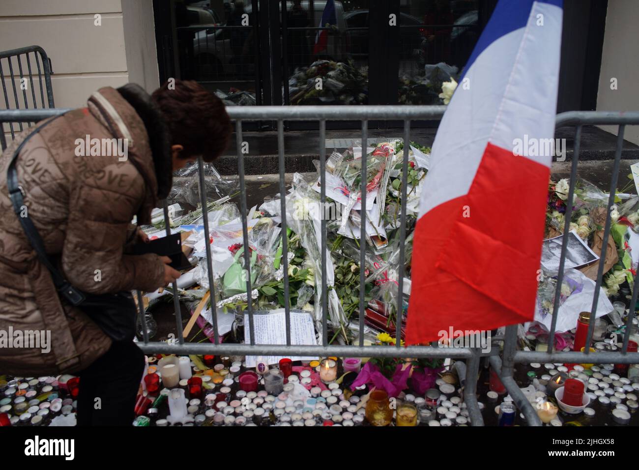 Eine Frau steht vor Blumen, Kerzen, Botschaften und Fotos, um an die Opfer der Pariser Anschläge vom 2015. November zu erinnern. Le Bataclan Music venue, 50 Boulevard Voltaire, Paris, Frankreich - Paris greift an - ein Jahr nach dem Stockfoto