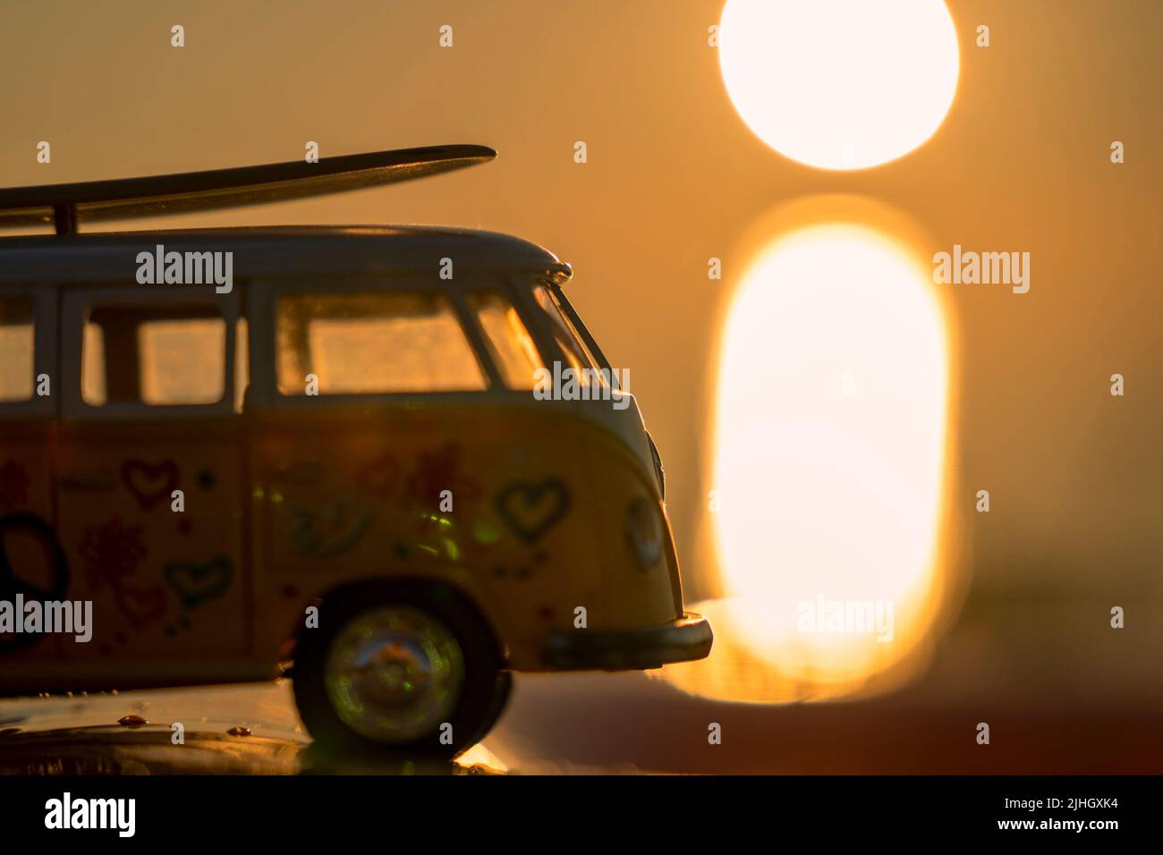 Minibus mit Surfen auf dem Dach in den Strahlen der untergehenden Sonne Stockfoto