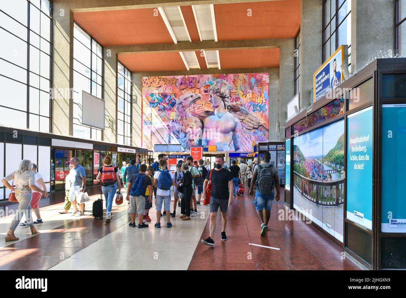 Heidelberg, Deutschland - Juli 2022: Im Inneren des Heidelberger Hauptbahnhofs mit Reisenden und Graffiti-Wandbild namens 'Ganymede und der Adler' des Künstlers Due Pi Stockfoto