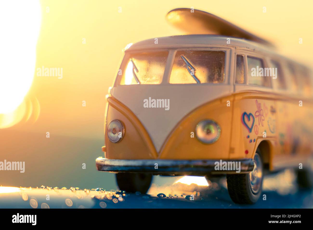 Minibus mit Surfen auf dem Dach in den Strahlen der untergehenden Sonne Stockfoto