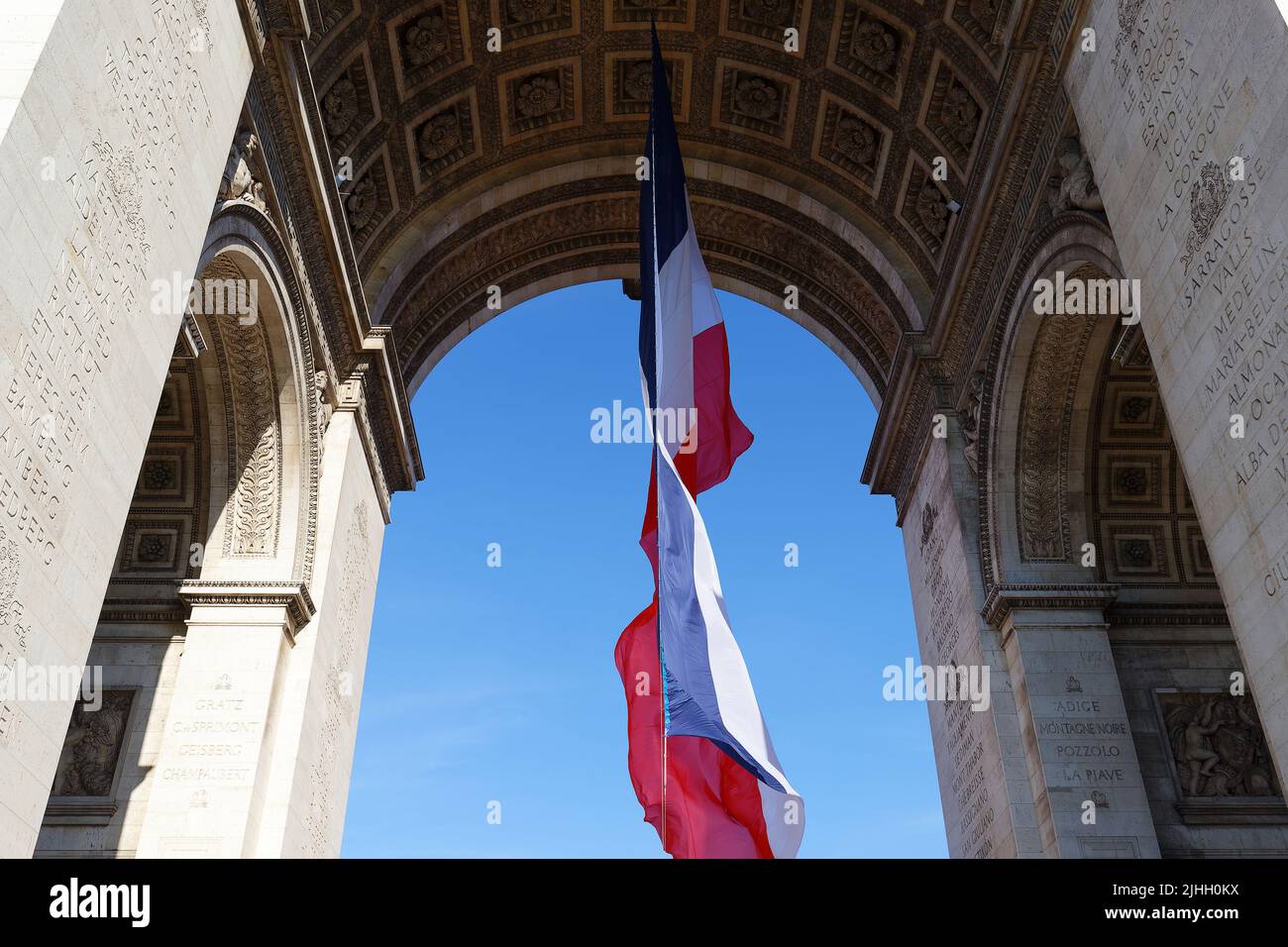 Die französische Flagge unter dem Triumphbogen. Das Grab des unbekannten Soldaten. Paris, Frankreich. Inschrift auf Bogen in Französisch: Namen von Schlachten -Eigenwort Stockfoto