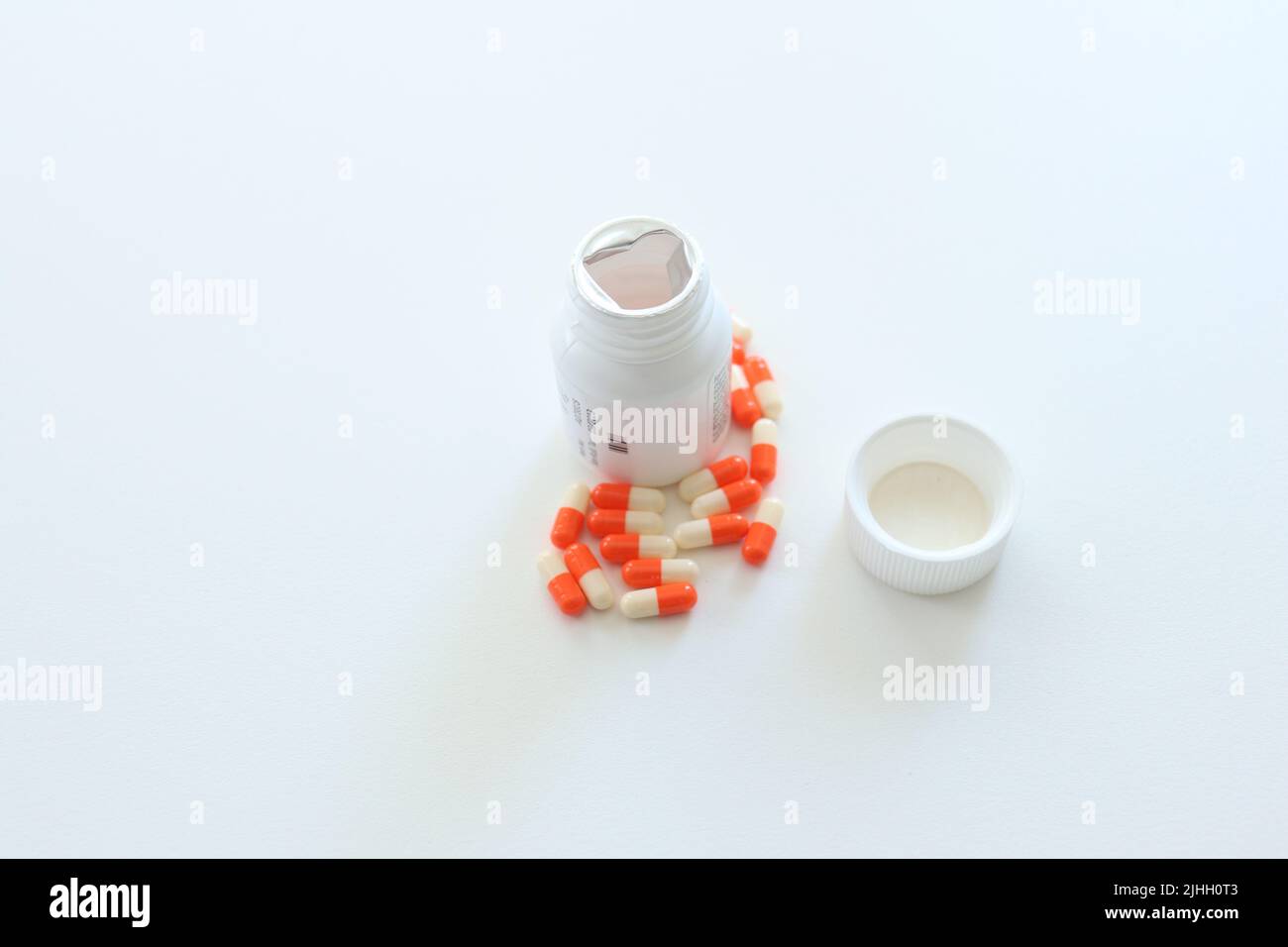 Medikamentenkiste und verstreute orangefarbene, weiße Pillen auf weißem Hintergrund isoliert. Über Einnahme von Medikamenten oder Drogenabhängigkeit ist sehr gefährlich. Selbstmordidee. Stockfoto