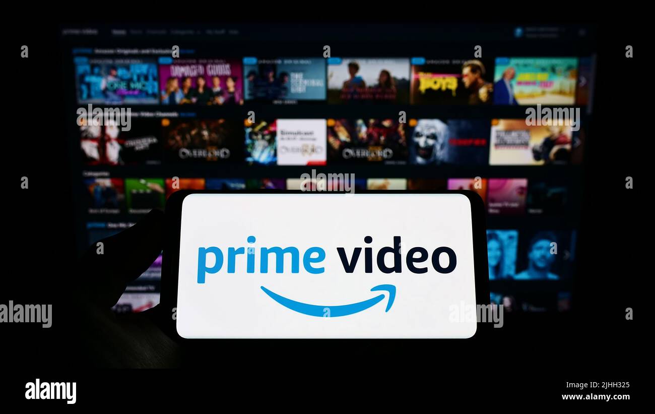 Person, die das Smartphone mit dem Logo des Streaming-Dienstes Amazon Prime Video auf dem Bildschirm vor der Website hält. Konzentrieren Sie sich auf die Telefonanzeige. Stockfoto