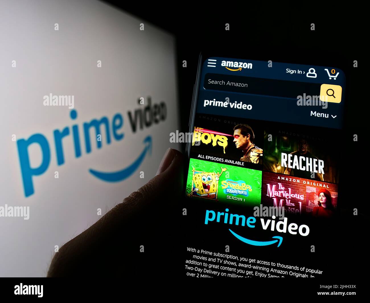 Person, die Mobiltelefon mit der Webseite des Streaming-Dienstes Amazon Prime Video auf dem Bildschirm vor dem Logo hält. Konzentrieren Sie sich auf die Mitte des Telefondisplays. Stockfoto