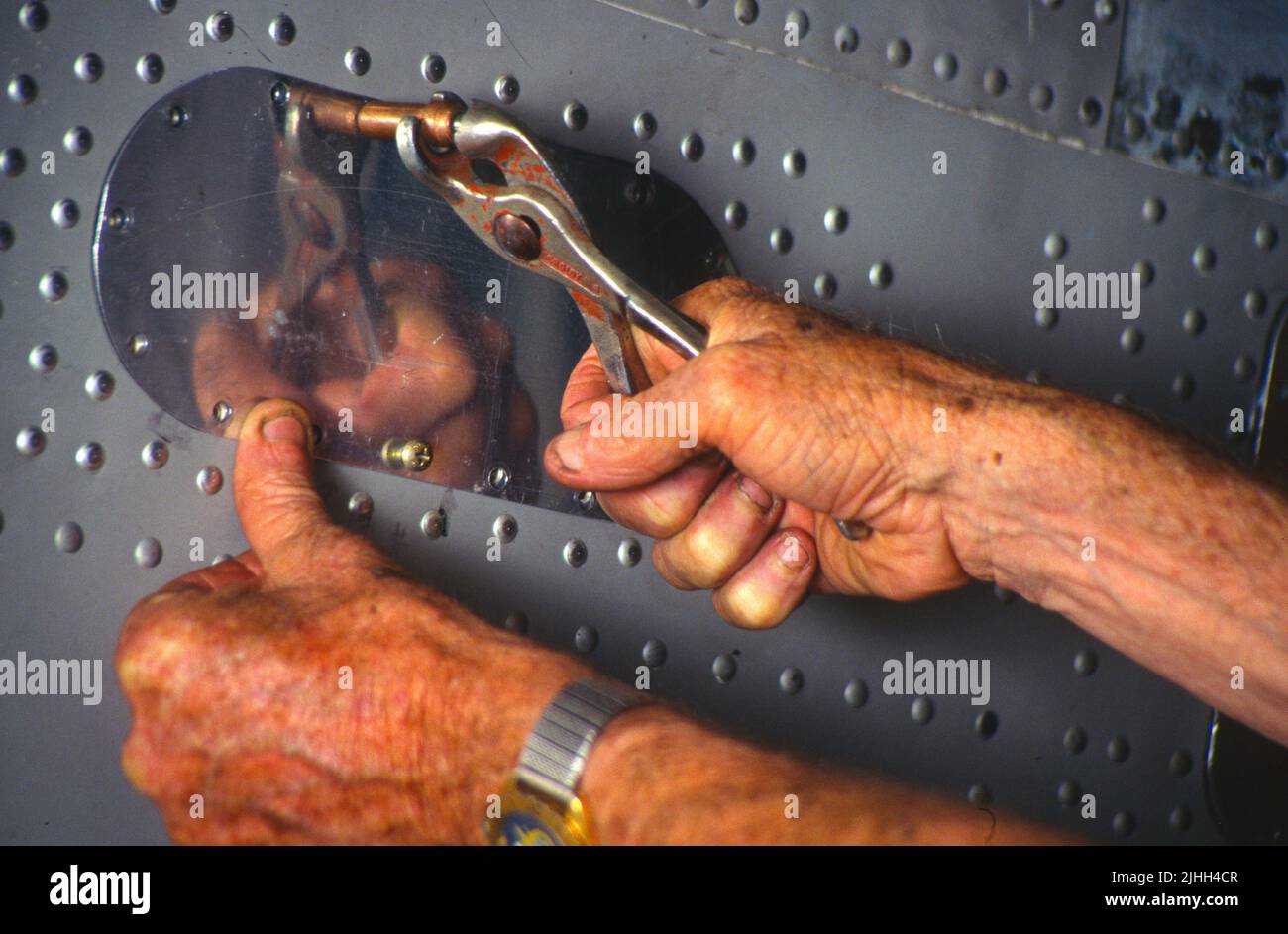 An einem Flugzeugrumpf arbeiten erfahrene Hände an einem Inspektionsschild Stockfoto