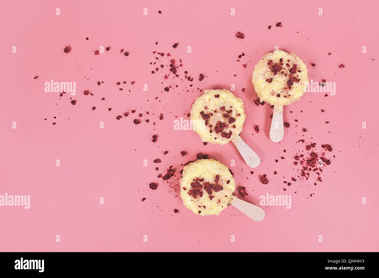 Eiscreme Lolly mit weißer Schokolade, Coconot und getrockneten Himbeer-Fruchtstücken auf rosa Hintergrund Stockfoto