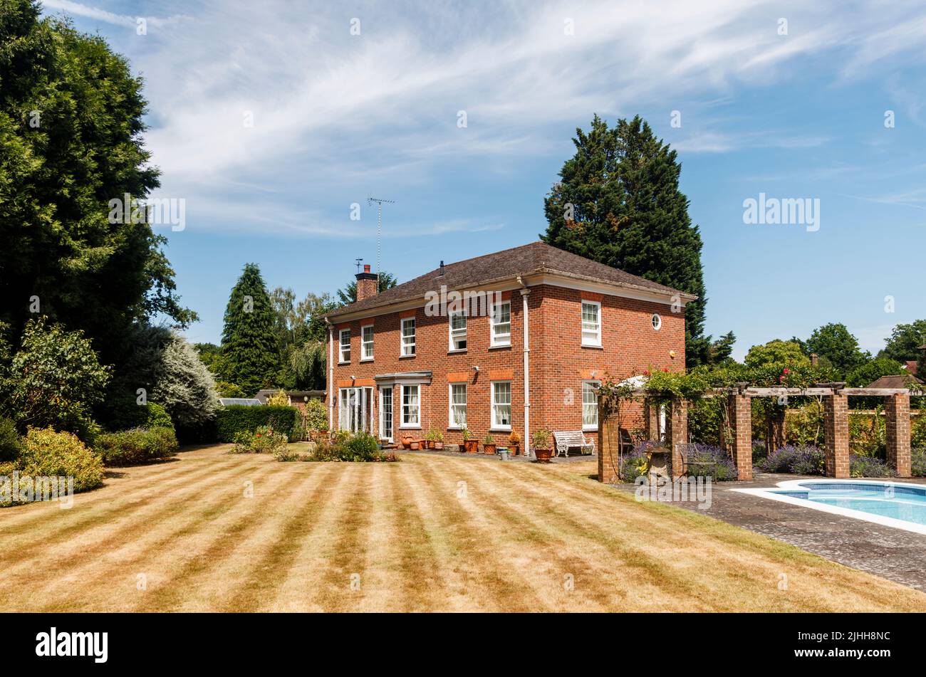 Außenansicht eines Einfamilienhauses, Garten und Schwimmbad, der Rasen mit Streifen, aber braun von Trockenheit und heißen Temperaturen im Sommer, Surrey, Großbritannien Stockfoto