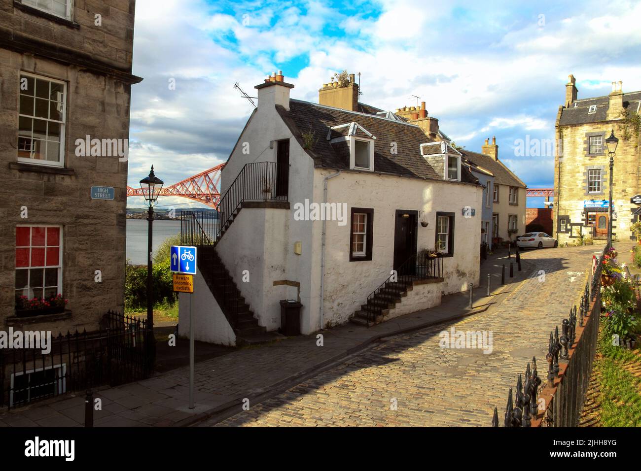 Schottische Stadt, malerisches weißes Haus in einer Kopfsteinpflasterstraße mit der Forth Bridge im Hintergrund, South Queensferry, Schottland, Großbritannien Stockfoto