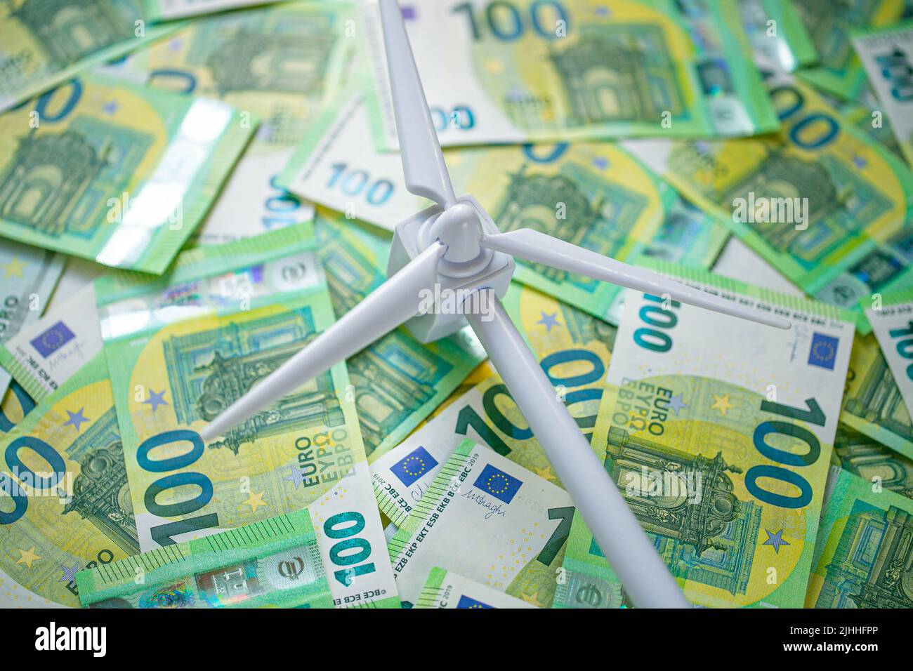 Kosten für Windenergie. Zahlung für Windenergie. Kosten für grüne erneuerbare Energie. Weißer Windgenerator auf grünen Euro Rechnungen Hintergrund. Alternative Energie . Stockfoto