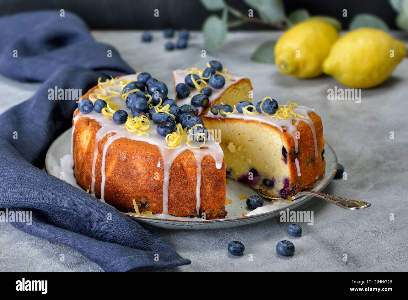Zitronen-Blaubeerkuchen mit süßem Zuckerguss, Beeren und Zitronenschale überzogen Stockfoto