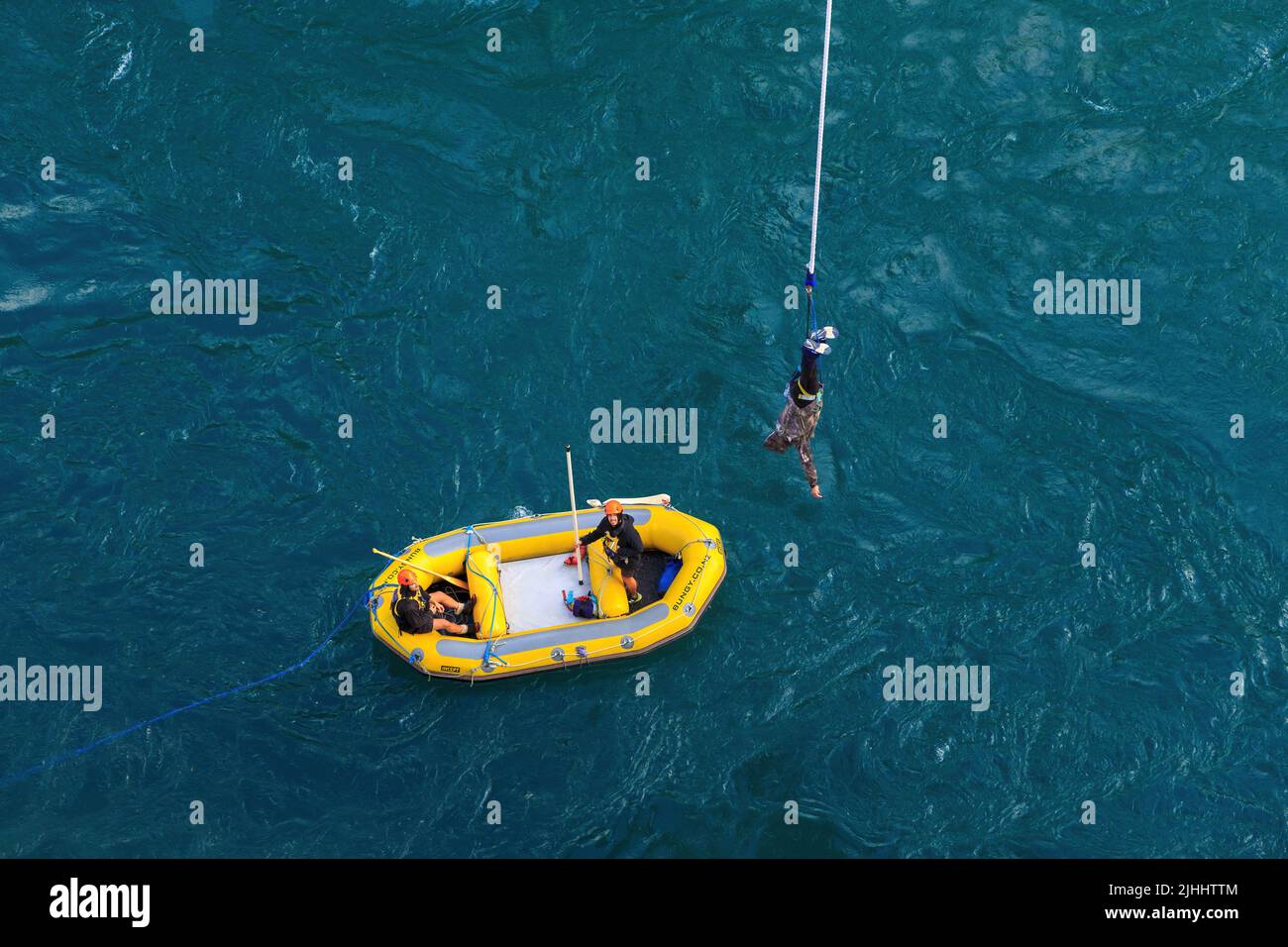 Ein Bungy Jumper, der über dem Kawarau River, Otago, Neuseeland, baumelt. Er wird gerade von einem Schlauchboot Der Firma A J Hackett abgeholt Stockfoto