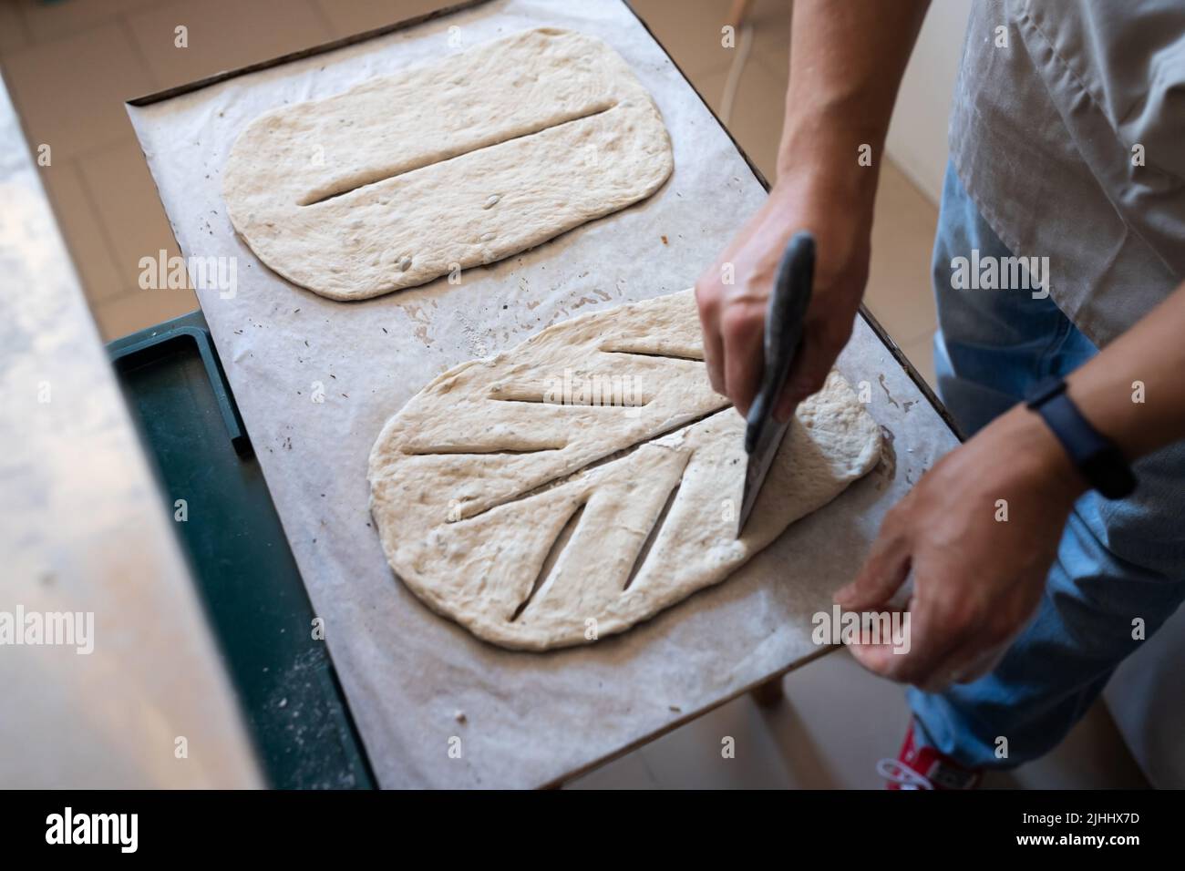 Ein Bäcker formt und schneidet traditionelles französisches Fougasse-Brot. Vorderansicht. Stockfoto