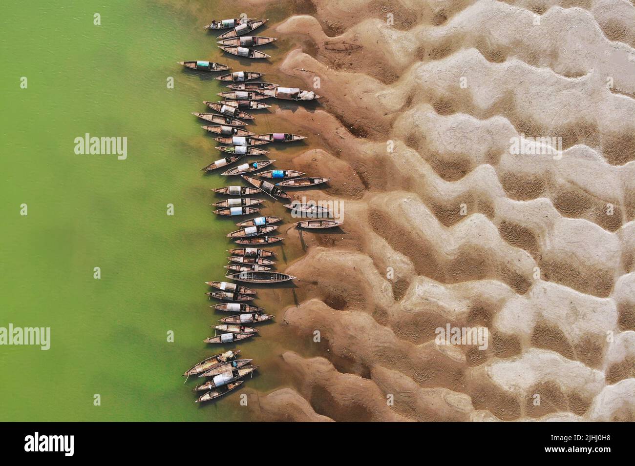 Am Flussufer sind hölzerne Boote aufgestellt, die verschiedene schöne visuelle Muster geschaffen haben. Stockfoto