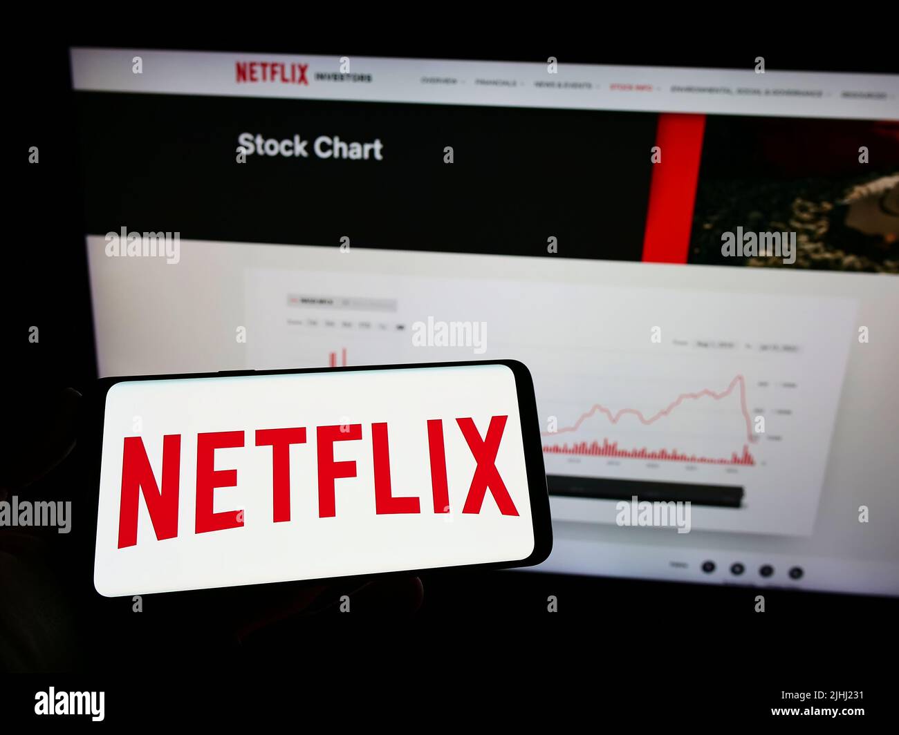Person, die ein Mobiltelefon mit dem Logo des amerikanischen Video-Streaming-Unternehmens Netflix Inc. Auf dem Bildschirm vor der Webseite hält. Konzentrieren Sie sich auf die Telefonanzeige. Stockfoto