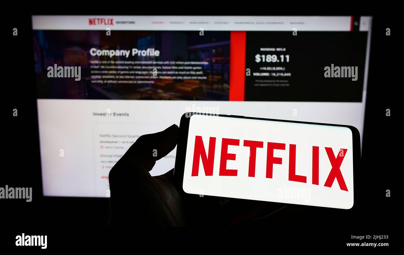 Person, die das Smartphone mit dem Logo des US-amerikanischen Video-Streaming-Unternehmens Netflix Inc. Auf dem Bildschirm vor der Website hält. Konzentrieren Sie sich auf die Telefonanzeige. Stockfoto